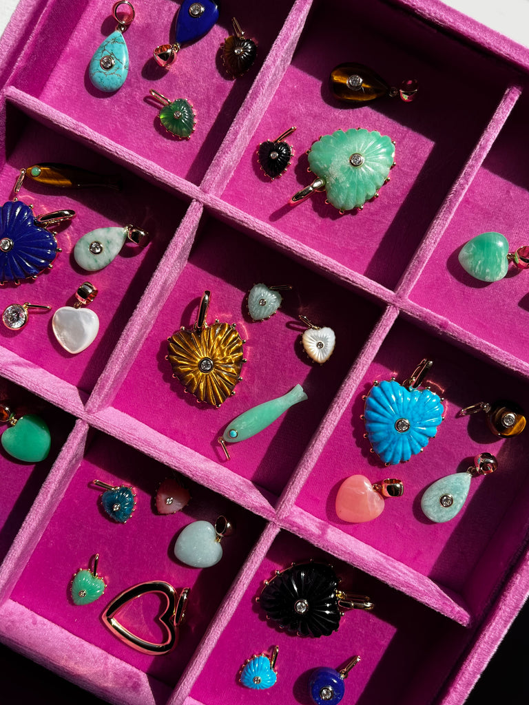 Pink jewelry box with compartments filled with various colorful earrings.